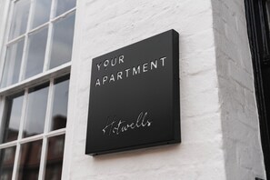 Uma placa preta numa parede branca com a inscrição 'YOUR APARTMENT Hotwells'.