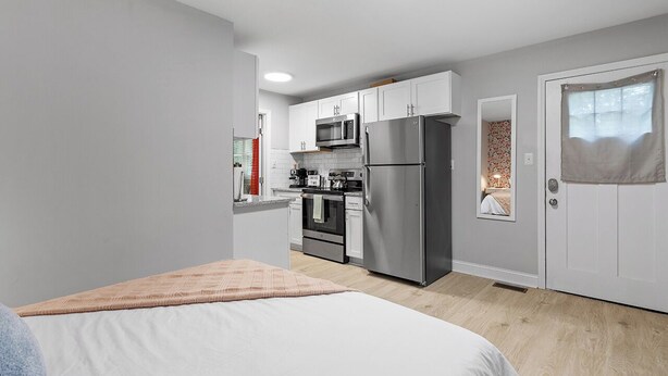 A compact hotel room with a kitchenette, a bed, and a bathroom. - Stylish studio ~ Self Check-In & Fast WiFi Near Downtown Raleigh (Raleigh)