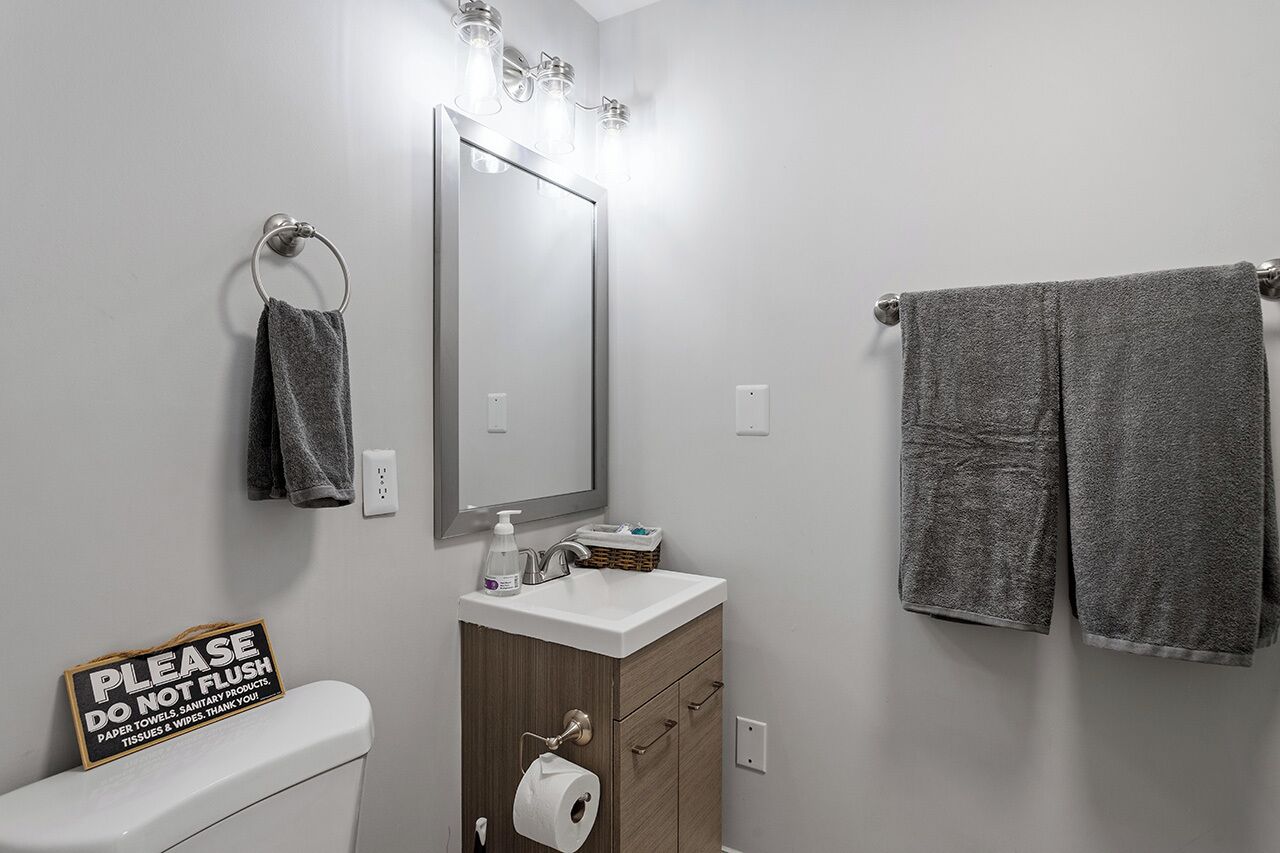 Un bagno con il water, un lavandino, uno specchio e un portasciugamani.