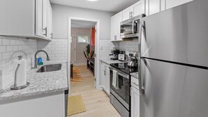 A modern kitchen with white cabinets, stainless steel appliances, and a patterned rug. - Stylish studio ~ Self Check-In & Fast WiFi Near Downtown Raleigh (Raleigh)