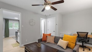 A modern living room with a gray sofa, wooden coffee table, and a ceiling fan. - Stylish studio ~ Self Check-In & Fast WiFi Near Downtown Raleigh (Raleigh)