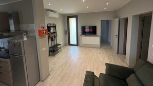 A modern living room with a flat-screen TV, a sofa, and a kitchen area with a refrigerator and a small table. - Accommodation located 26 km from Milan, 9.9 km from Como and 15 km from Switzerland. (Manera)