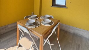 A dining area with a wooden table set for four, white chairs, and a window with a view. - Accommodation located 26 km from Milan, 9.9 km from Como and 15 km from Switzerland. (Manera)