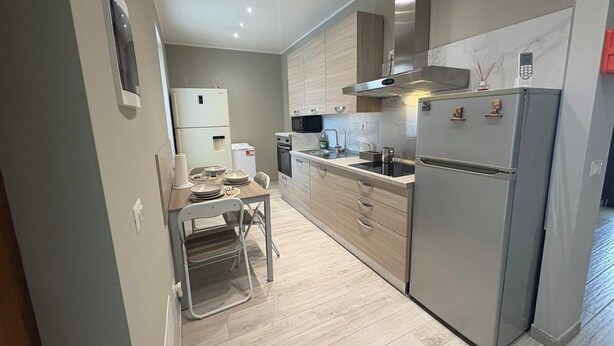 A modern kitchen with a built-in oven, stainless steel appliances, and a dining area with a table and chairs. - Accommodation located 26 km from Milan, 9.9 km from Como and 15 km from Switzerland. (Manera)