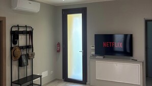 A modern living room with a flat-screen TV, a wall-mounted air conditioner, and a door with frosted glass. - Accommodation located 26 km from Milan, 9.9 km from Como and 15 km from Switzerland. (Manera)