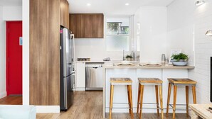 A modern kitchen with wooden cabinets, stainless steel appliances, and a white tiled backsplash. - Ocean Views At Cottesloe Beach (Cottesloe)