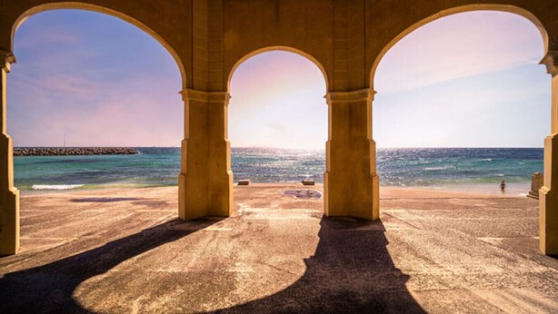 A beach view through a structure with three arches, a sandy beach, and the ocean. - Ocean Views At Cottesloe Beach (Cottesloe)