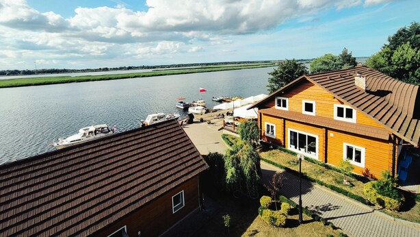 A riverside property with a wooden house, a dock with boats, and a clear view of the river. - Studio for 4 People in Swinoujscie (Swinoujscie)