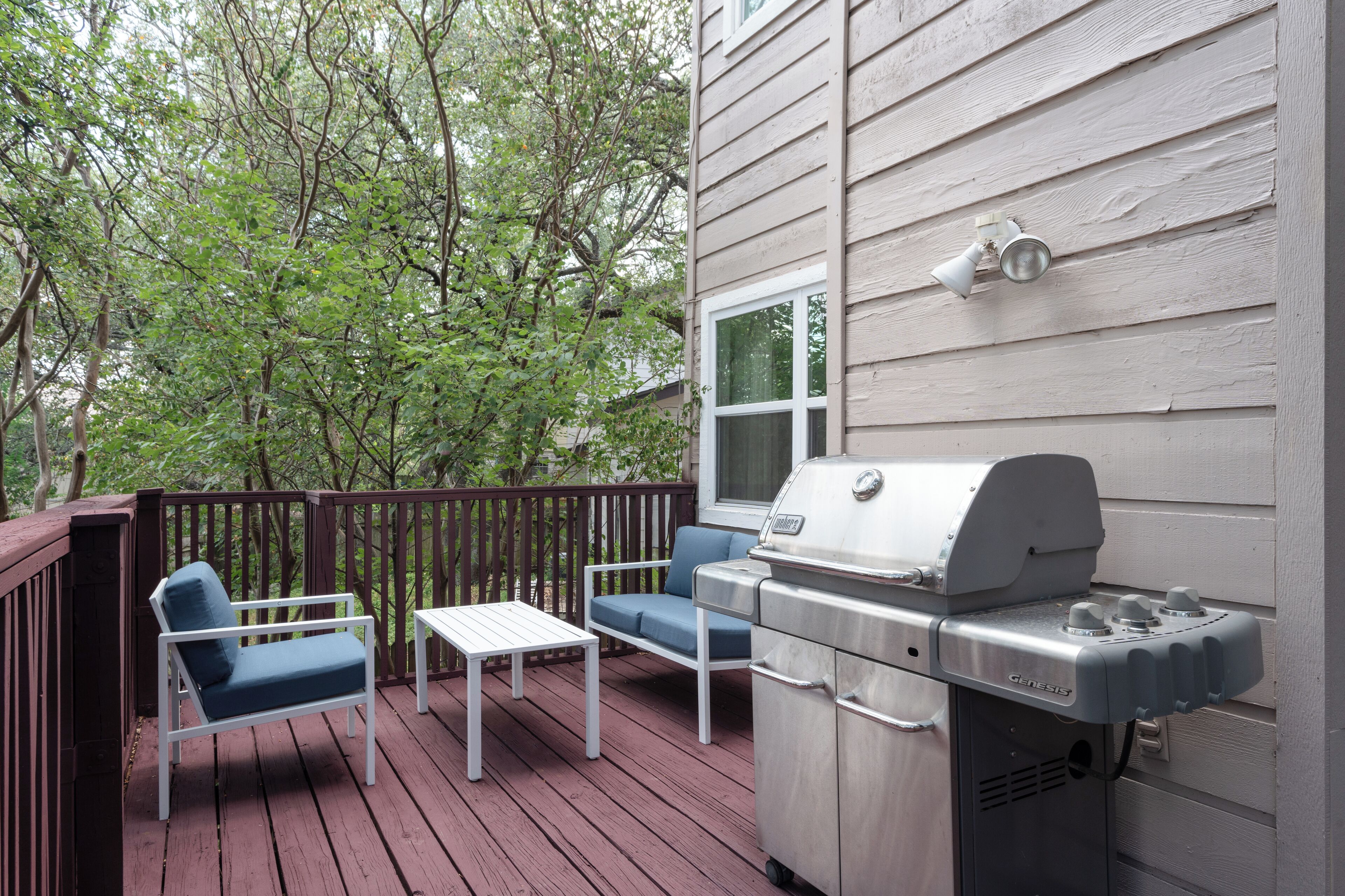A deck with a grill, two chairs, and a table.