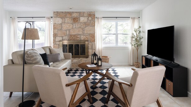 A living room with a stone fireplace, a sofa, a coffee table, and a TV.