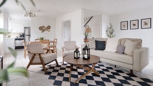 A modern living room with a checkered floor, a round coffee table, and a sofa with cushions.