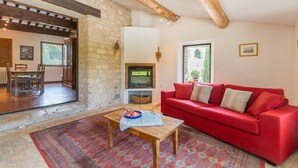 A living room with a red sofa, wooden coffee table, patterned rug, stone wall, wooden beams, and a fireplace. - Holiday Home 'Bastide Provençale' with Private Pool, Private Terrace and Private Garden (Caseneuve)