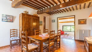 A dining area with a wooden table and chairs, a large cabinet, and a view through an open doorway. - Holiday Home 'Bastide Provençale' with Private Pool, Private Terrace and Private Garden (Caseneuve)