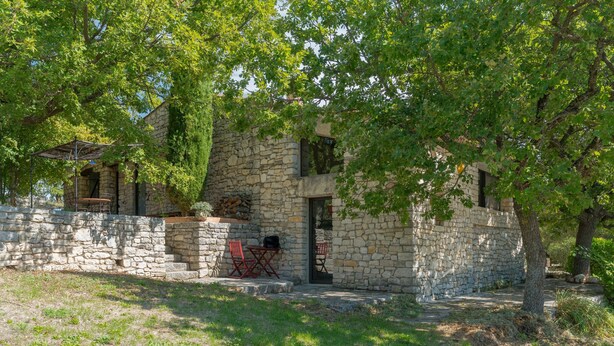 A stone building with a door, a small outdoor seating area, and a tree in front. - Holiday Home 'Bastide Provençale' with Private Pool, Private Terrace and Private Garden (Caseneuve)