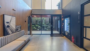 A modern lobby with a seating area, a vending machine, and a fire extinguisher. - Urbic Sabiá (São Paulo)