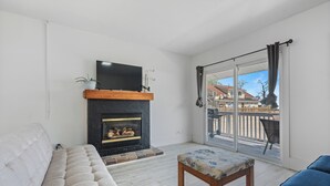 A living room with a fireplace, a sofa, a bench, and a balcony with a view.
