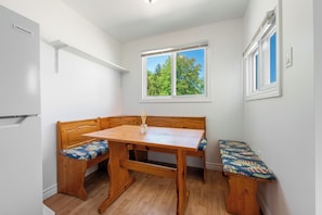 A room with a wooden bench, a table, and a window with a view of trees.