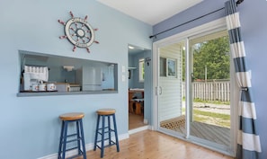 A room with a kitchen area, two stools, a sliding glass door leading to a deck, and a 'WELCOME ABOARD' sign.