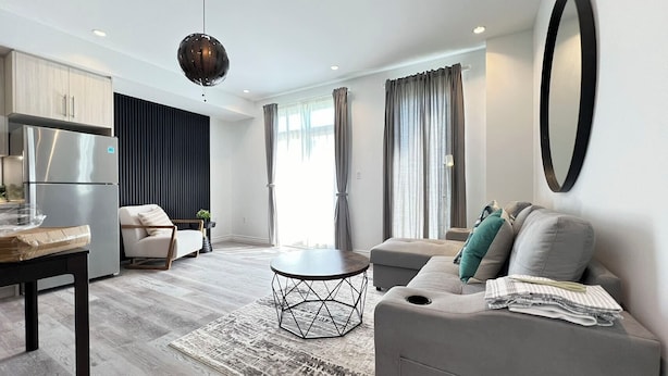 Una sala de estar moderna con un sofá, una mesa de comedor y una zona de cocina con un refrigerador.
