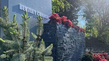 Une enseigne pour le complexe résidentiel Fallsview Townhouse, avec un mur en pierre et des fleurs rouges.