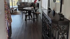 A spacious living area with a dining table, a sofa, and a balcony with sliding doors.