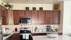 A modern kitchen with wooden cabinets, stainless steel appliances, and a central island with stools.
