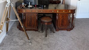 A wooden desk with a computer, a chair, and a telescope.