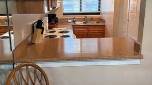 A kitchen with a built-in island, wooden cabinets, a stove, and a window with blinds.