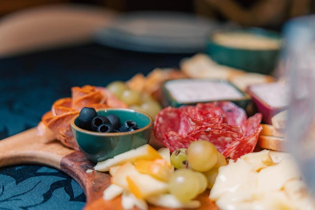 A charcuterie board with various cheeses, fruits, and olives.