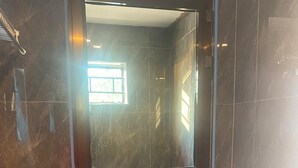 A modern bathroom with a glass-enclosed shower, dark marble walls, and a visible toilet. - Capricorn by Quest (Cape Maclear)