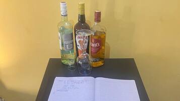 Una mesa con un cuaderno, tres botellas de licor y un vaso.