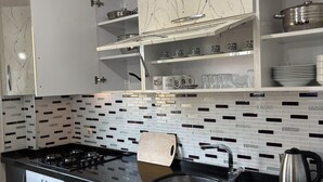 Cozinha moderna com armários preto e branco, bancada preta e painel de azulejos.