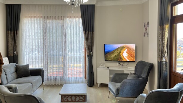 Uma sala de estar moderna com sofá, poltronas, mesa de centro e televisão sobre um móvel.