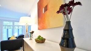 A modern living room with a white sofa, a lamp, a vase with flowers, and a basket of apples on a white table. - "Relaxed vacation days await you in the apartment Sergio 1 on Norderney!" (Norderney)