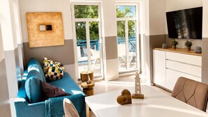 Ein modernes Wohnzimmer mit einem blauen Sofa, einem Couchtisch und einem an der Wand montierten Fernseher.