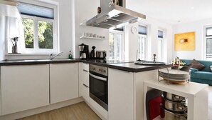 Eine moderne Küche mit weißen Schränken, einem schwarzen Backofen und einer Edelstahl-Dunstabzugshaube.