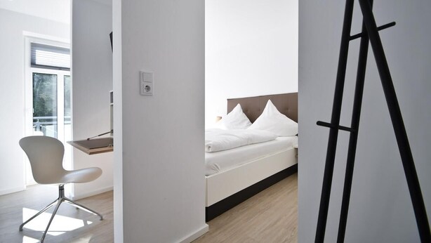 Ein modernes Hotelzimmer mit Bett, Schreibtisch und Stuhl.