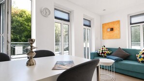 Ein modernes Wohnzimmer mit Esstisch, Sofa und einer Uhr an der Wand.