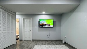 Una sala de estar moderna con un televisor de pantalla plana en la pared, una alfombra estampada y un banco de madera.