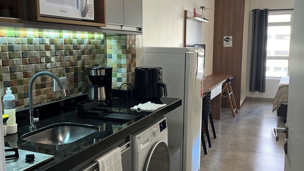 Et moderne køkken med indbygget mikroovn, kaffemaskine og vaskemaskine.
