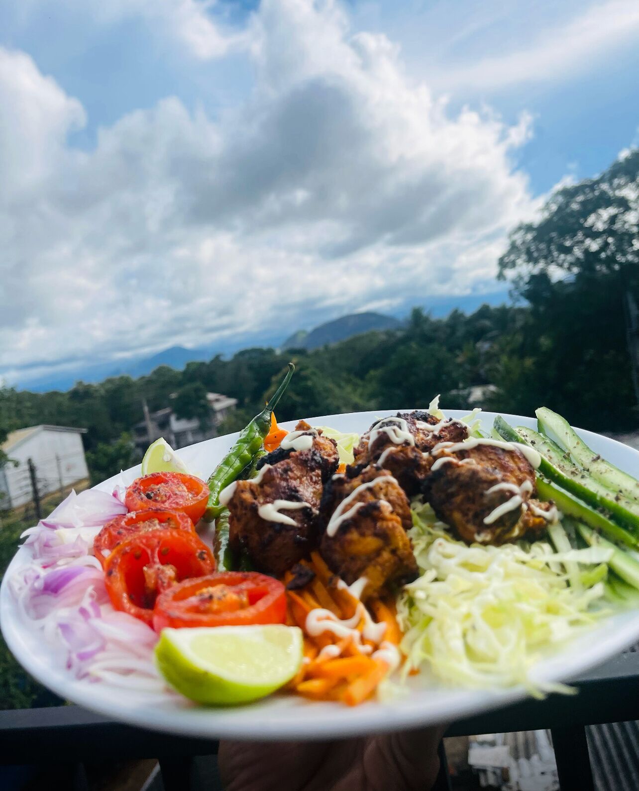 A plate of food with grilled meatballs, vegetables, and a lime wedge.