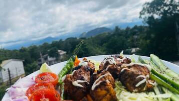 Un plato de comida con albóndigas a la parrilla, verduras y un gajo de lima.