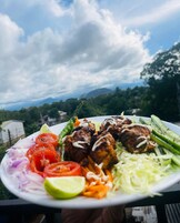 Un plato de comida con albóndigas a la parrilla, verduras y un gajo de lima.
