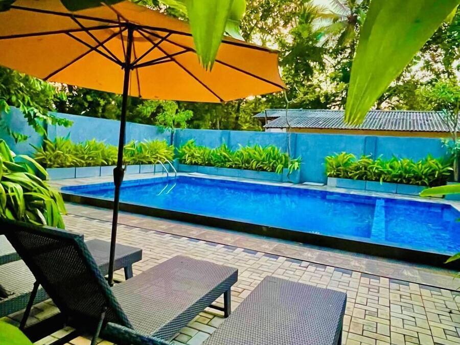 Zona de piscina con sillones de descanso y una sombrilla.