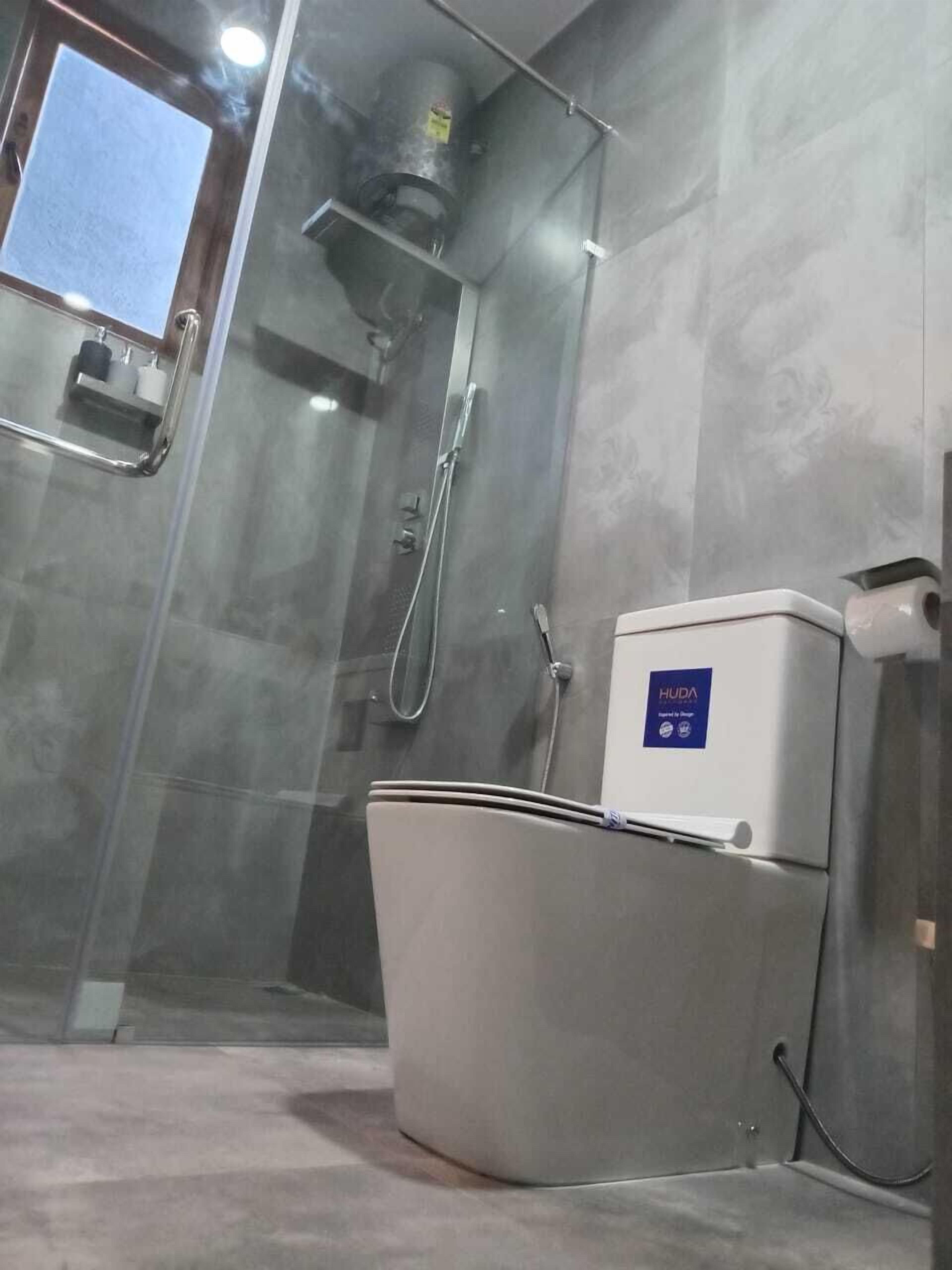 A bathroom with a glass-enclosed shower, a toilet, and a water heater.