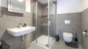 A modern bathroom with a glass-enclosed shower, a white sink, and a toilet.
