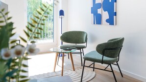 Una habitación moderna con dos sillas verdes, una mesa de vidrio y una obra de arte abstracto en la pared.