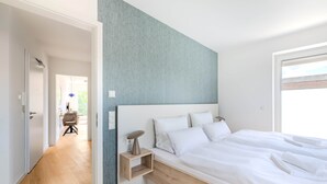 Un dormitorio moderno con una cama grande, una mesita de noche y vistas al exterior.