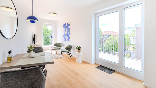 Una sala de estar moderna con comedor, ventanas amplias y vista al exterior.