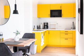 A modern kitchen with yellow cabinets, a black microwave, and a coffee maker. - Ohmstede (Oldenburg)